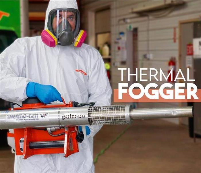 a man in PPE holding a thermal fogger