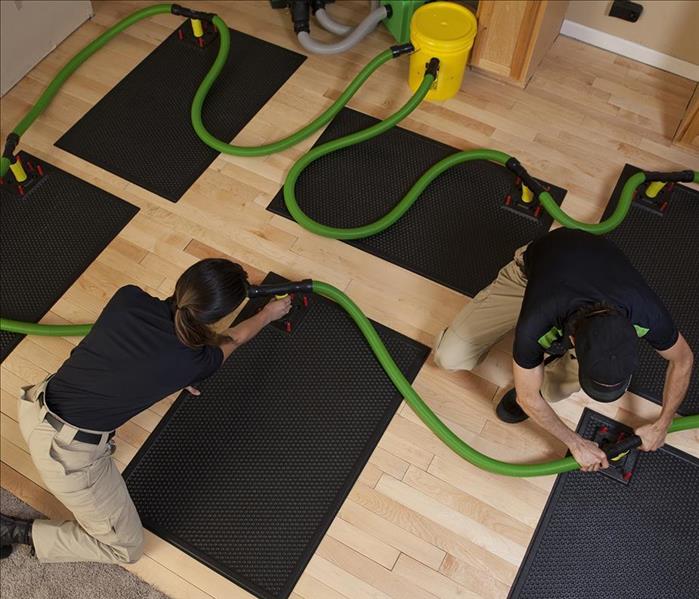 Two people setting up the floor mat drying system